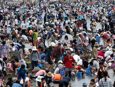Sejumlah pengunjung menggali pasir untuk berburu kerang di pantai kawasan Yokohama, dekat Tokyo, Senin (30/4). Puluhan ribu orang berdesakan di pantai selama Golden Week atau periode liburan di Jepang pada akhir April hingga awal Mei. (AP/Koji Sasahara)