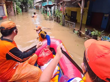 Petugas PPSU membawa bantuan nasi bungkus untuk warga yang bertahan saat banjir di kawasan pemukiman Jalan Bango, Pondok Labu, Jakarta Selatan, Sabtu (20/2/2021). Banjir akibat luapan Kali Krukut yang melanda sejak semalam menyebabkan pemukiman tergenang hingga dua meter. (merdeka.com/Arie Basuki)