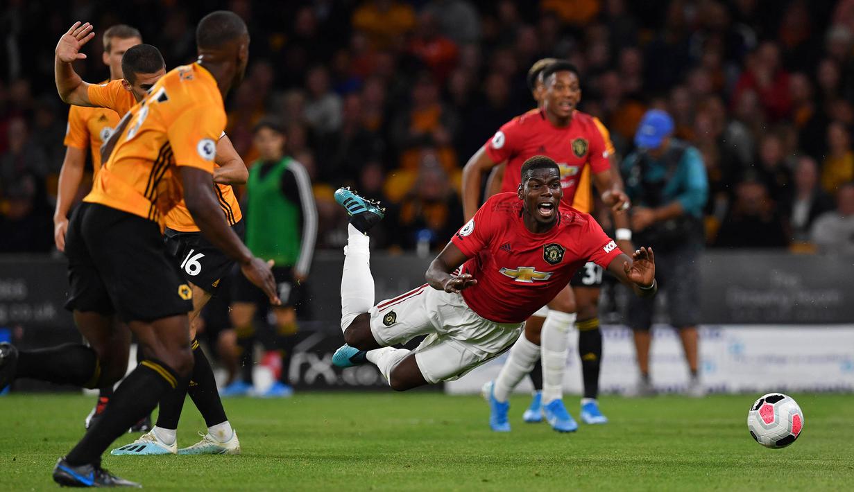 Gelandang Manchester United, Paul Pogba, dijatuhkan di kotak penalti saat melawan Wolverhampton pada laga Premier League di Stadion Molineux, Wolverhampton, Senin (19/8). Kedua klub bermain imbang 1-1. (AFP/Paul Ellis)