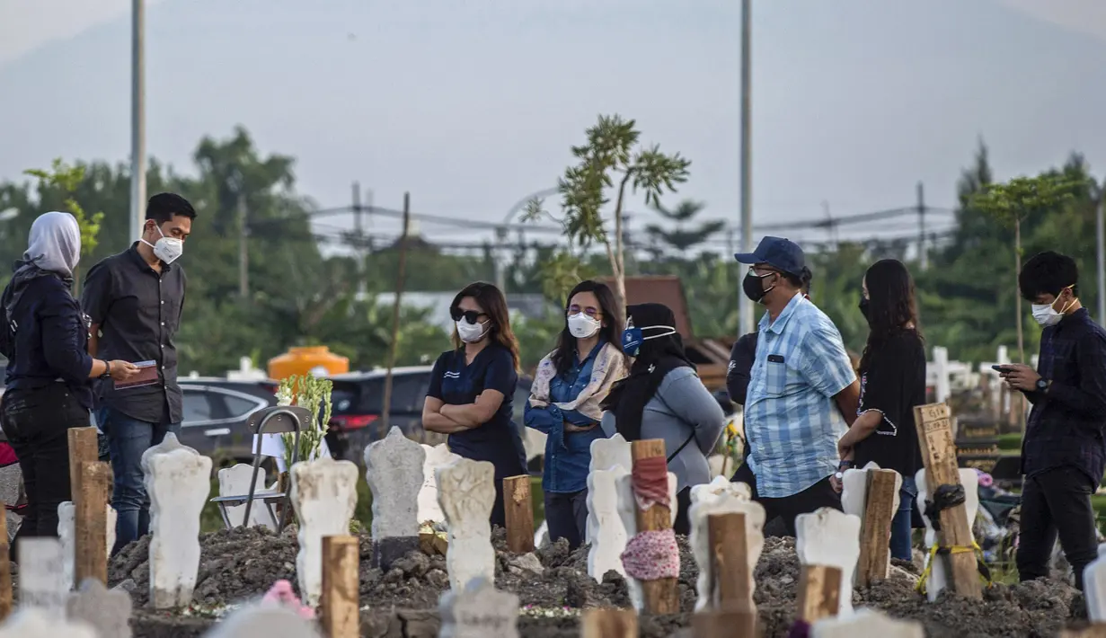 Keluarga berdoa untuk kerabat mereka di lokasi pemakaman korban virus corona COVID-19 di TPU Keputih, Surabaya, Jawa Timur, Sabtu (17/7/2021). Di Kota Surabaya terdapat dua tempat lahan pemakaman khusus blok COVID-19 yakni TPU Keputih dan TPU Babat Jerawat. (JUNI KRISWANTO/AFP)