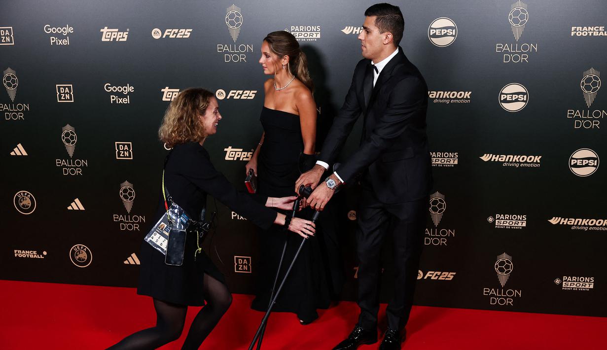 Pemain Manchester City, Rodri menggunakan tongkat bantu saat menghadiri penghargaan Ballon d'Or 2024 pada acara yang berlangsung di Theatre du Chatelet, Paris, Selasa (29/10/2024) dini hari WIB. (AFP/Franck Fife)