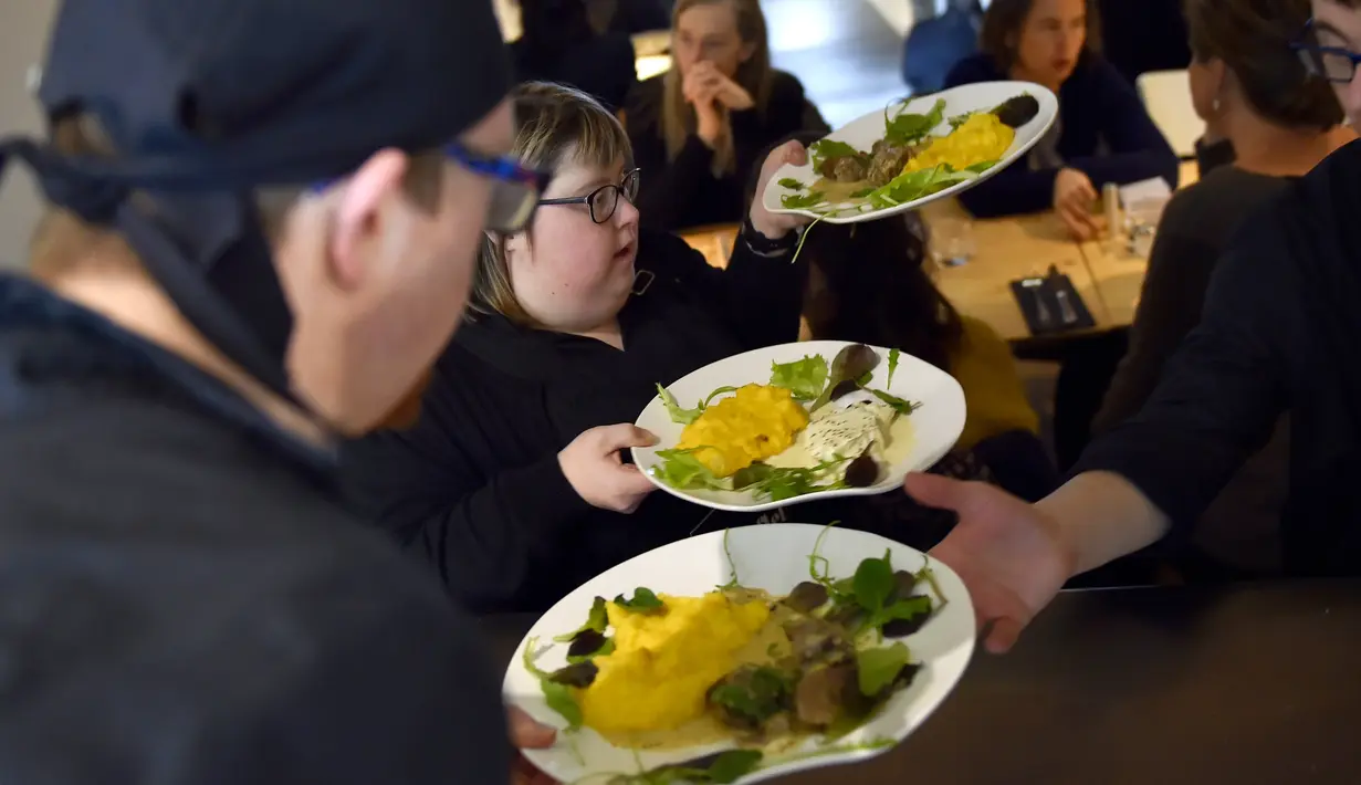 Pelayan dengan down syndrome saat akan mengantarkan pesanan kepada pengunjung restoran "Le Reflet" di Nantes, Prancis Barat, 9 Februari 2017. Lelievre (26), mempekerjakan sejumlah karyawan yang memiliki down syndrome di restorannya. (LOIC VENANCE/AFP)
