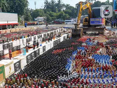 Petugas menggunakan alat berat eskavator saat memusnahkan minuman keras ilegal hasil penindakan di Kantor Pusat Bea Cukai, Jakarta Timur, Rabu (31/7/2024). (merdeka.com/Arie Basuki)