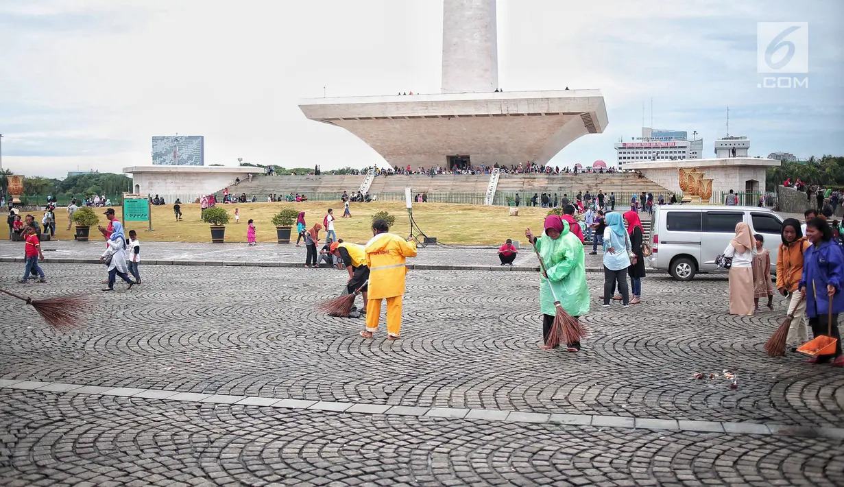 Petugas kebersihan membersihkan sisa sampah usai perayaan Tahun Baru 2019 di Monas, Jakarta, Selasa (1/1). Total sampah di DKI Jakarta saat perayaan Tahun Baru 2019 berkurang dari tahun lalu. (Liputan6.com/Faizal Fanani)