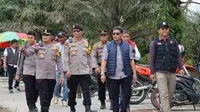 Kapolres Pelalawan AKBP Suwinto bersama polisi lainnya menuju TPS untuk melihat proses pencoblosan. (Liputan6.com/M Syukur)