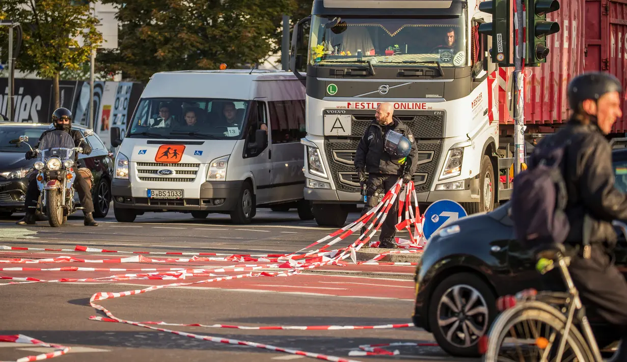 Polisi melepas tali plastik yang dipakai dalam pemblokiran Jembatan Jannowitz di Berlin, Jerman, Jumat (20/9/2019). Selain memblokir Jembatan Jannowitz, aktivis juga membentangkan spanduk bertulis 'salam hangat dari Berlin'. (AXEL SCHMIDT/AFP)