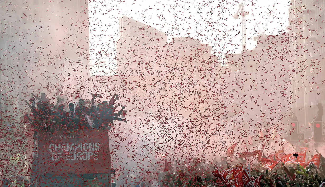 Para pemain Liverpool menyapa fans saat parade juara Liga Champions 2019 di Liverpool, Minggu (2/6). Ribuan fans tumpah ruah di jalanan untuk merayakan keberhasilan pemain membawa pulang trofi Si Kuping Besar ke kota Liverpool. (AP/Barrington Coombs)