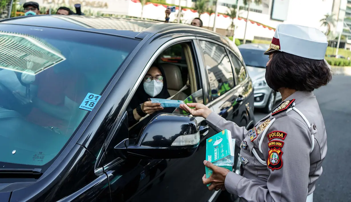 Petugas kepolisian membagikan masker saat sosialisasi pelaksanaan ganjil genap di Kawasan Bundaran HI, Jakarta, Minggu (2/8/2020). Ditlantas Polda Metro Jaya kembali memberlakukan sistem ganjil genap di 25 ruas jalan protokol  DKI Jakarta mulai Senin, 3 Agustus 2020. (Liputan6.com/Faizal Fanani)