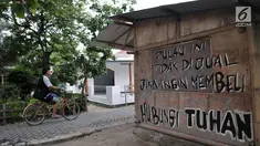 Wisatawan bersepeda melintasi coretan protes di salah satu tembok rumah di Pulau Pari, Kepulauan Seribu, Jakarta, Minggu (29/4). Coretan dibuat warga yang menolak klaim PT Bumi Pari Asri atas kepemilikan lahan Pulau Pari. (Merdeka.com/Iqbal S. Nugroho)