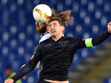 Striker Lazio, Miroslav Klose, berebut bola dengan pemain Dnipropetrovsk, Dmytro Chygrynskiy, dalam lanjutan Grup G Liga Europa yang berlangsung di Stadion Olimpico, Roma, Jumat (27/11/2015) dini hari WIB. (AFP Photo/Gabriel Bouys)