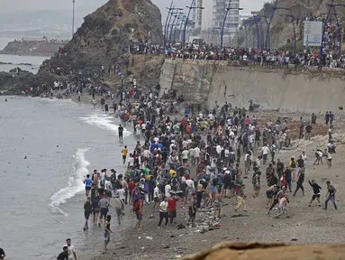Para imigran berkumpul di sepanjang pagar di lokasi bentrokan dekat Fnideq, di perbatasan Maroko-Spanyol, Jumat, 31 Juli 2026. (AFP/  Abdel Majid Bziouat)