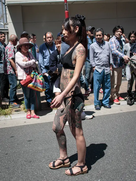Peserta dengan tato tradisional di tubuhnya mengikuti Festival Sanja Matsuri di luar kuil Sensoji, distrik Asakusa, Tokyo, Minggu (20/5). Hampir dua juta orang mengunjungi Asakusa selama tiga hari di saat festival tersebut berlangsung. (AFP/Behrouz MEHRI)