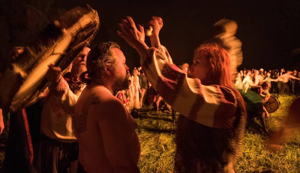 Prosesi upacara ritual pagan kuno yang digelar di dekat desa Glubokovo, Rusia (24/6). Usai membuat api unggun besar, mereka menari dan bernyanyi, melompat di atas api untuk menyambut musim yang baru. (AFP Photo/Andrei Borodulin)