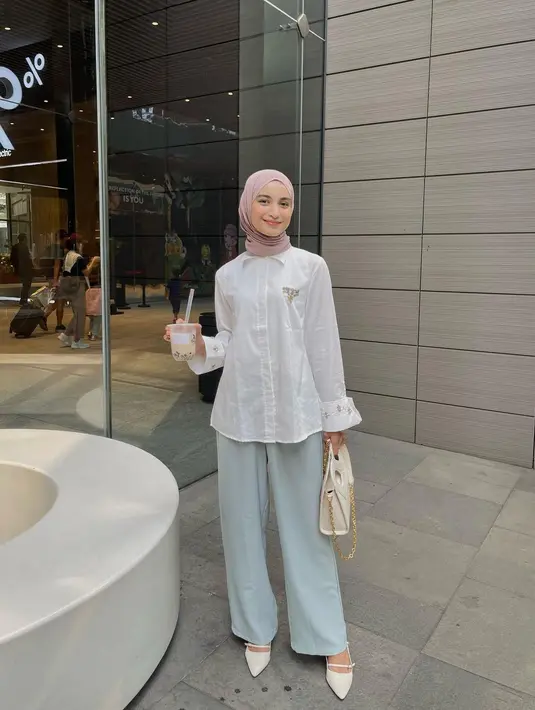 Padu padan manis ala Cut Intan Nabila mengenakan atasan poplin shirt berwarna putih dengan celana panjang biru muda, hijab ungu muda, dan heels putih. [Foto: Instagram/cut.intannabila]