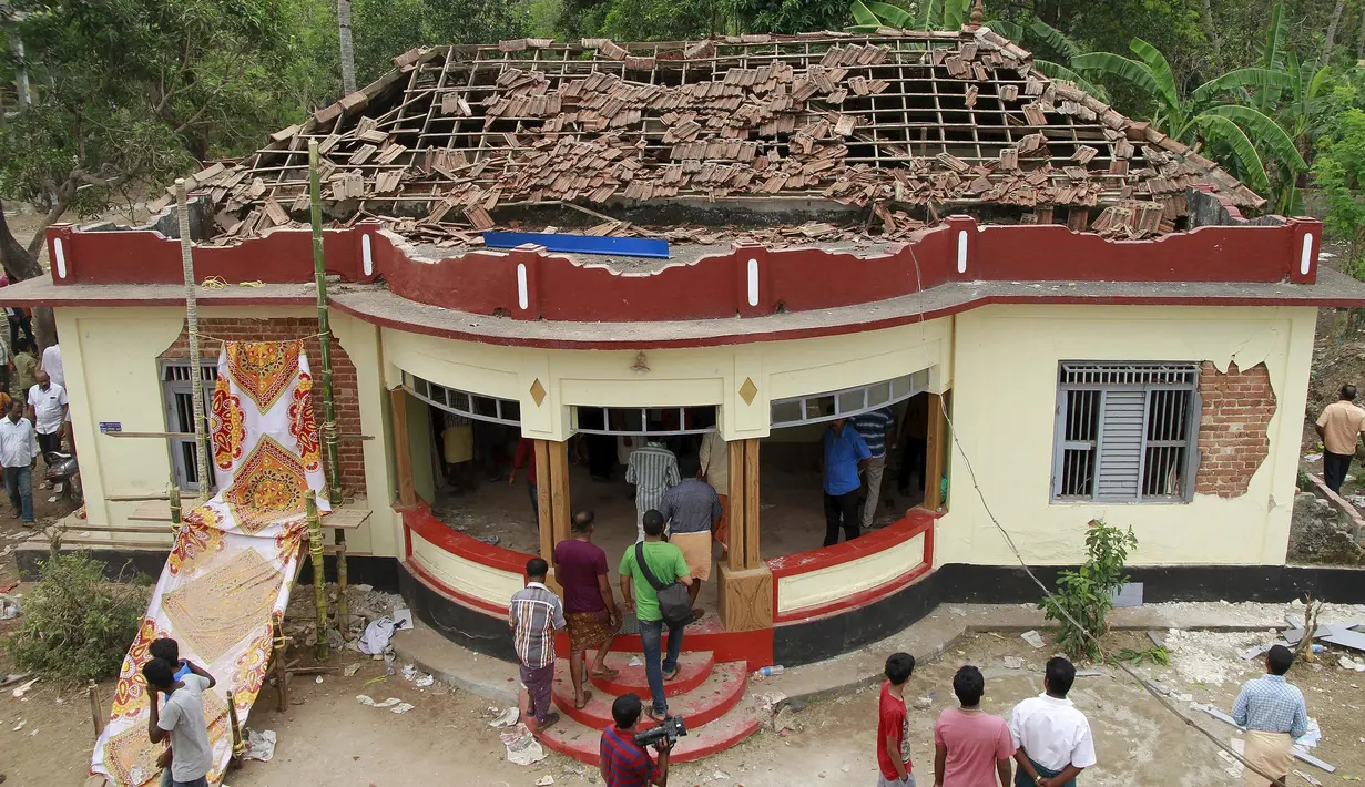 Warga berkumpul di sebuah kuil yang rusak akibat kebakaran di Kollam, India Selatan, Minggu (10/4). Media setempat melaporkan, kebakaran terjadi setelah perayaan yang menyalakan kembang api untuk menandai akhir sebuah festival. (REUTERS/Sivaram V)