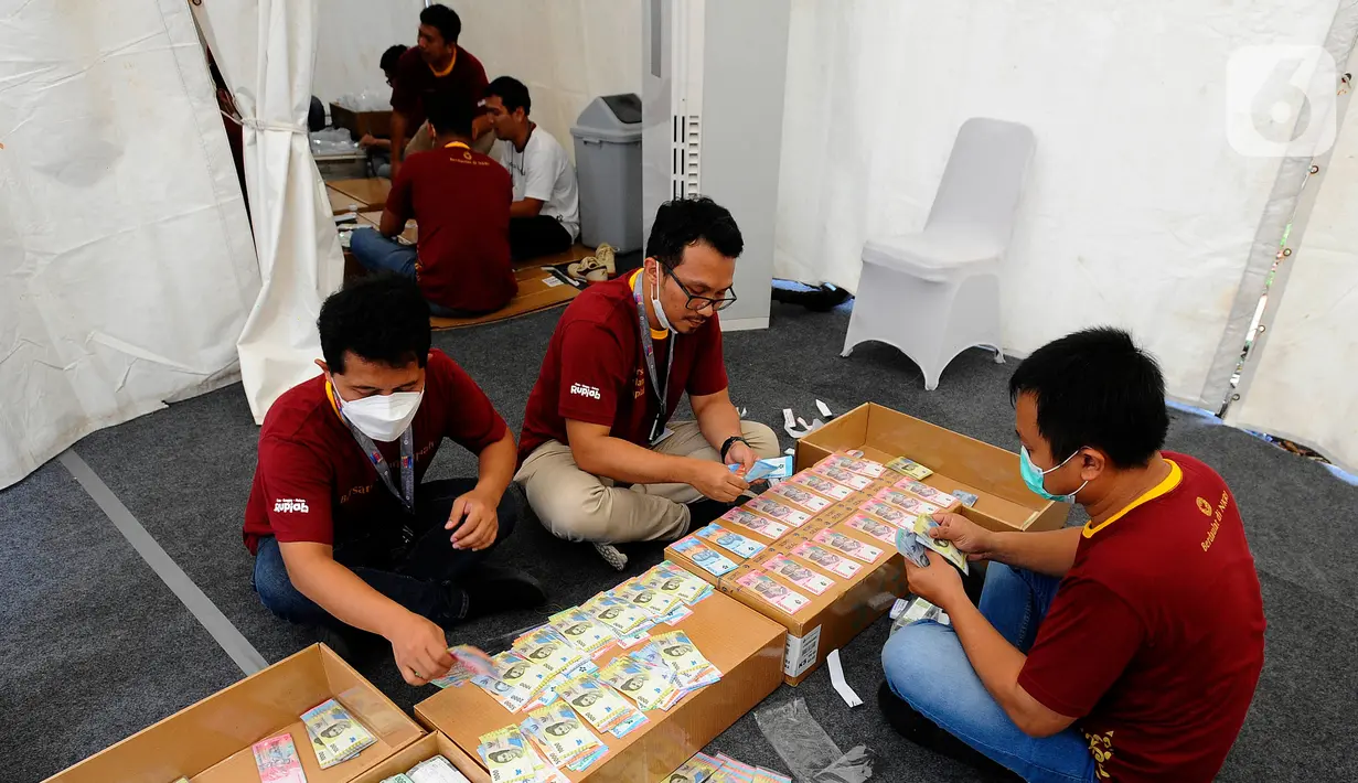 Petugas menata uang rupiah kertas tahun emisi 2022 saat membuka penukaran untuk warga di Hall Basket Gelora Bung Karno (GBK), Jakarta, Minggu (21/8/2022). Uang baru TE 2022 memiliki kualitas lebih baik yang menjamin masa edar lebih lama serta teknologi unsur pengamanan semakin sulit untuk dipalsukan. (merdeka.com/Arie Basuki)