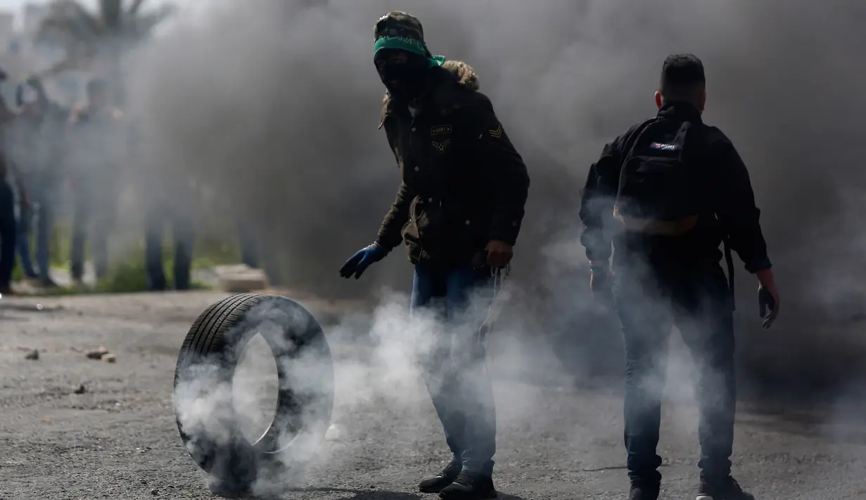 Pengunjuk rasa Palestina membakar ban saat bentrokan dengan pasukan Israel di pinggiran Kota Ramallah, Tepi Barat, Rabu (27/3). Bentrokan ini sebagai bentuk protes terhadap tahanan Palestina yang berada di Israel. (AP Photo/Majdi Mohammed)