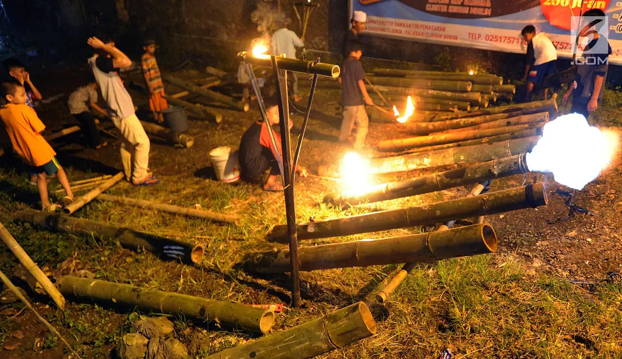 Anak-anak bermain meriam bambu atau bledugan saat merayakan malam takbiran di kawasan Cijeruk, Bogor, Jawa Barat, Selasa (4/6/2019). Tradisi yang dilakukan setiap malam Idul Fitri ini tetap dipertahankan oleh warga setempat. (merdeka.com/Arie Basuki)