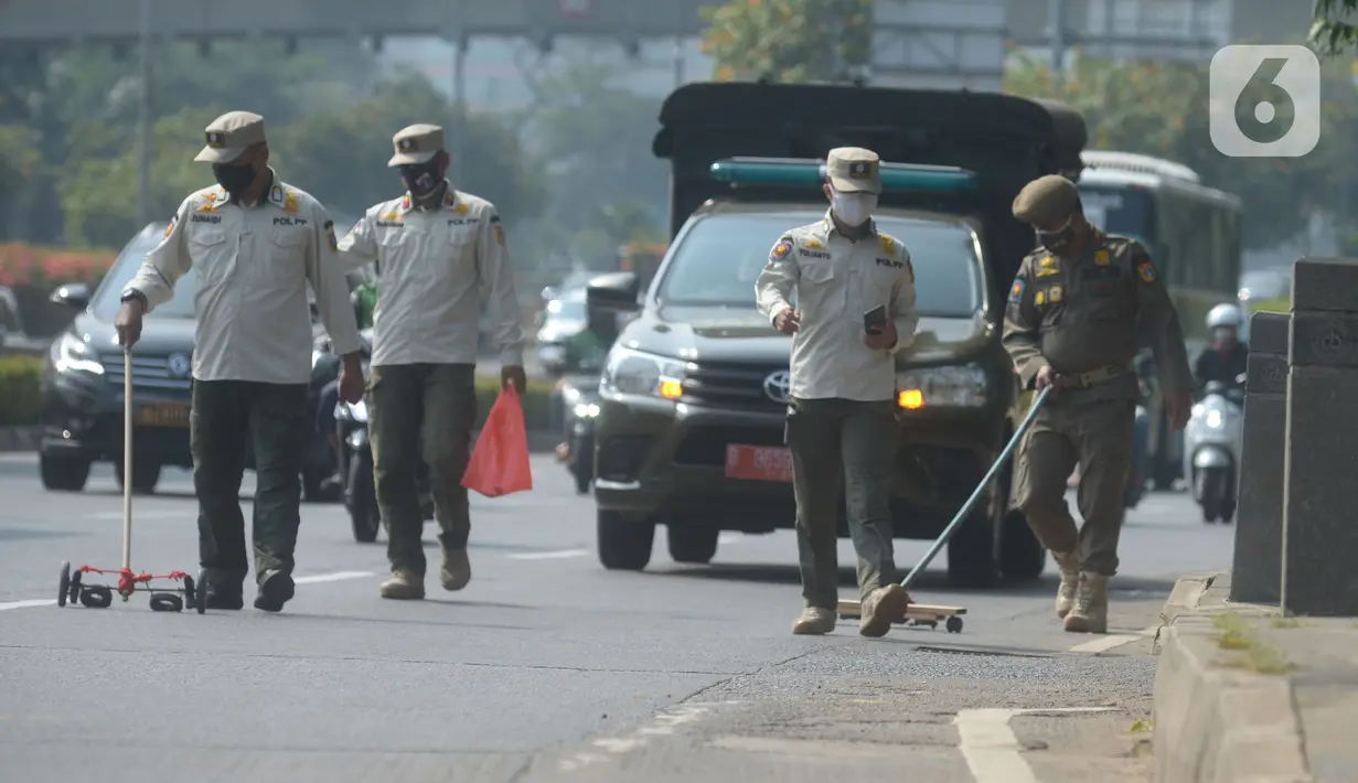 Petugas Satpol PP melakukan penyisiran Jalan Gatot Subroto dari ranjau paku di Jakarta, Sabtu (16/10/2021). Kegiatan penertiban ranjau paku ini untuk memberikan rasa aman dan nyaman bagi pengendara saat melintas di jalanan. (merdeka.com/Imam Buhori)