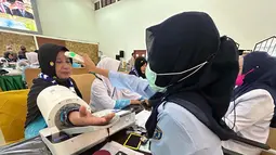 Kedatangan ini menandai dimulainya fase operasional pemberangkatan jemaah haji Indonesia tahun 1447 Hijriah/2026 Masehi. Tampak dalam foto, petugas memeriksa kesehatan calon haji setibanya di Asrama Haji Pondok Gede, Jakarta, Selasa (21/4/2026). (merdeka.com/Arie Basuki)