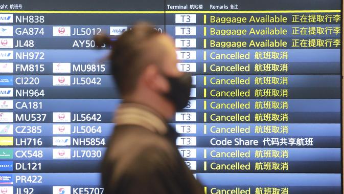 Seorang pria melewati papan informasi penerbangan di Bandara Internasional Haneda di Tokyo, Senin (28/12/2020). Jepang untuk sementara waktu melarang semua pendatang asing yang bukan penduduk masuk sebagai bentuk antisipasi varian baru COVID-19 hingga akhir Januari 2021. (AP Photo/Koji Sasahara)