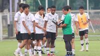 Bima Sakti (hijau) memberikan instruksi kepada para pemain Timnas Indonesia U-17 dalam sesi latihan di Lapangan ABC, Kompleks Gelora Bung Karno, Jakarta, Kamis (27/7/2023) pagi. (Bola.com/Abdul Aziz)
