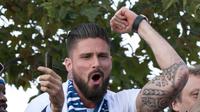 Striker timnas Prancis, Olivier Giroud berada di atas bus beratap terbuka saat parade merayakan juara Piala Dunia 2018 di sepanjang Champs Elysees, Paris, Senin (16/7). Prancis meraih trofi Piala Dunia kedua usai mengalahkan Kroasia. (AP/Claude Paris)