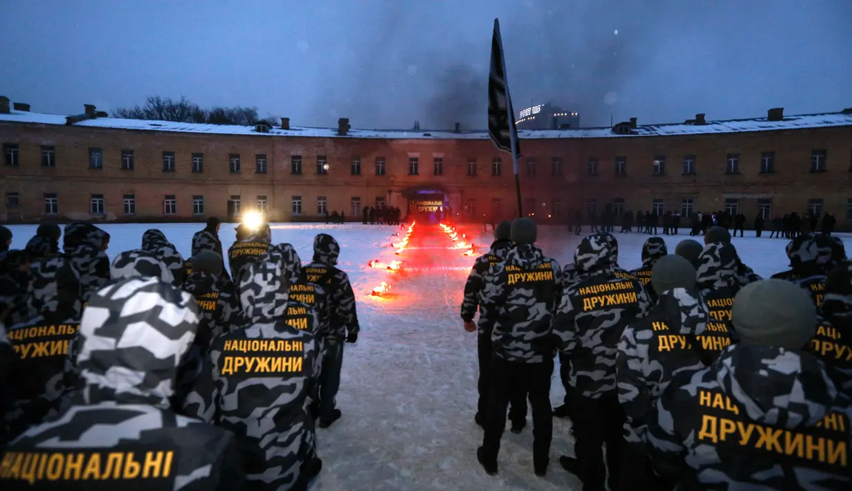 Relawan paramiliter sayap kanan Azov Civil Corps bersumpah setia di halaman sebuah benteng kota tua di pusat Kiev, Ukraina, Minggu (28/1). Tulisan di punggung mereka berbunyi: "Paramiliter Nasional". (AP Photo/Efrem Lukatsky)