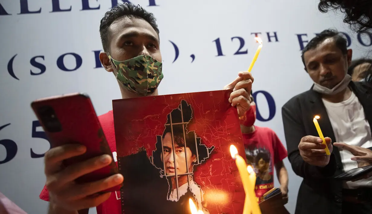 Warga Myanmar yang tinggal di Thailand memegang foto pemimpin Myanmar Aung San Suu Kyi dan menyalakan lilin saat protes di depan Kedutaan Besar Myanmar di Bangkok, Thailand, Kamis (4/2/2021). Warga memprotes kudeta militer yang terjadi Myanmar. (AP Photo/Sakchai Lalit)
