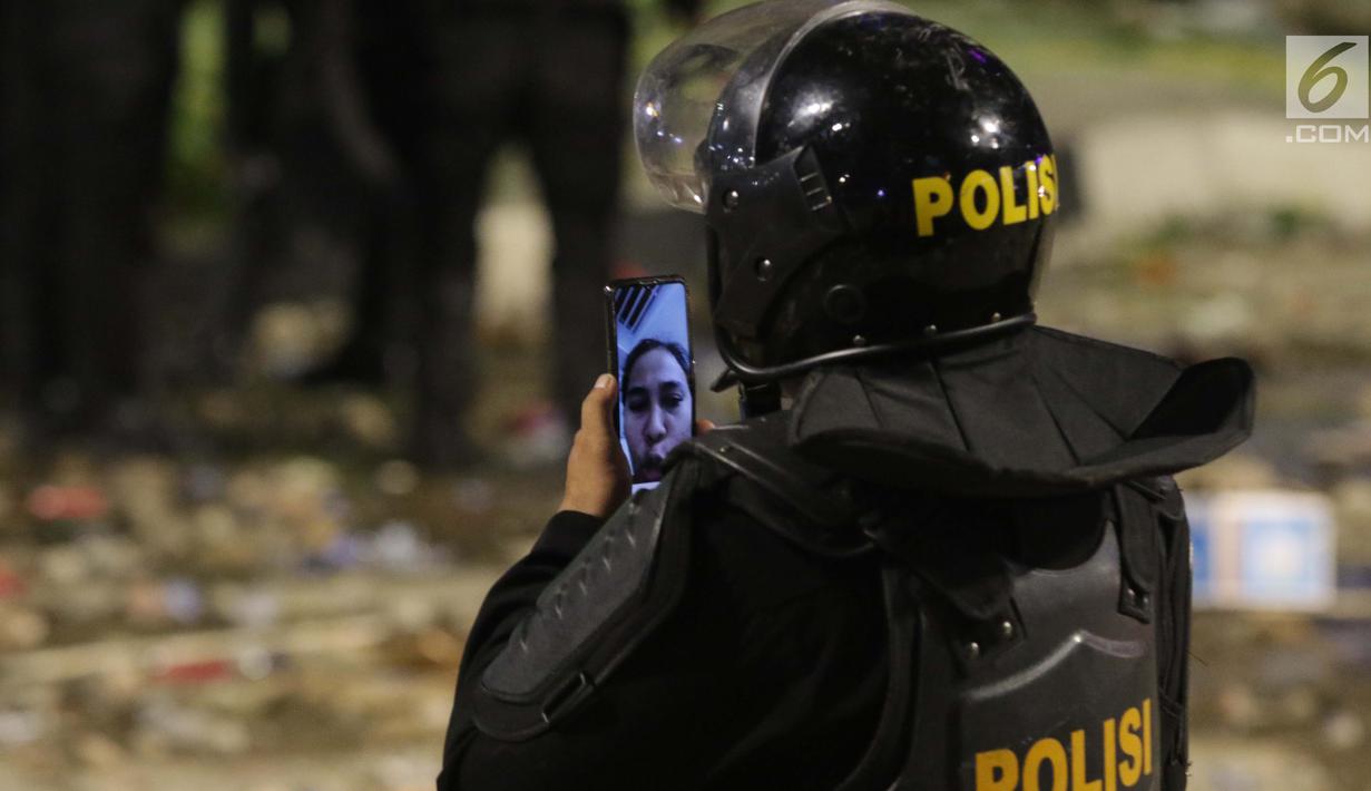 Personil Kepolisian dari satuan Brimob berkomunikasi dengan kerabatnya di sela-sela saat menghalau massa yang berlaku anarkis di sekitar depanGedung Bawaslu, Jalan MH Thamrin, Jakarta, Rabu (22/5/2019). Aksi unjuk rasa yang dimotori GNKR berakhir ricuh. (Liputan6.com/HelmiFithriansyah)