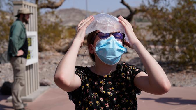 Katie Moore mendinginkan kepalanya dengan sekantong es di Taman Nasional Death Valley, California, AS, Senin (17/8/2020). Suhu terpanas di dunia terpantau terjadi di Taman Nasional Death Valley yang mencapai 130 derajat Fahrenheit (54,4 derajat Celcius) pada Minggu 16 Agustus. (AP Photo/John Locher)