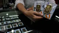 Pedagang menunjukan emas batangan 50 gram dan 100 gram di sebuah toko Kawasan Cikini, Jakarta, Kamis (3/9/2015). Harga emas milik PT Aneka Tambang Tbk (Antam) hari ini terpantau bergerak stabil di posisi Rp560 ribu per gram. (Liputan6.com/Johan Tallo)