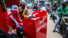 Seorang pekerja SPBU (kiri) menerima pembayaran dari pengendara yang mengantre untuk mengisi bahan bakar sepeda motor mereka di sebuah Stasiun Pengisian Bahan Bakar Umum (SPBU), Jakarta pada Rabu 1 April 2026. Pemerintah resmi tidak mengubah harga Bahan Bakar Minyak (BBM) di dalam negeri, baik harga BBM subsidi maupun non subsidi. (BAY ISMOYO/AFP)