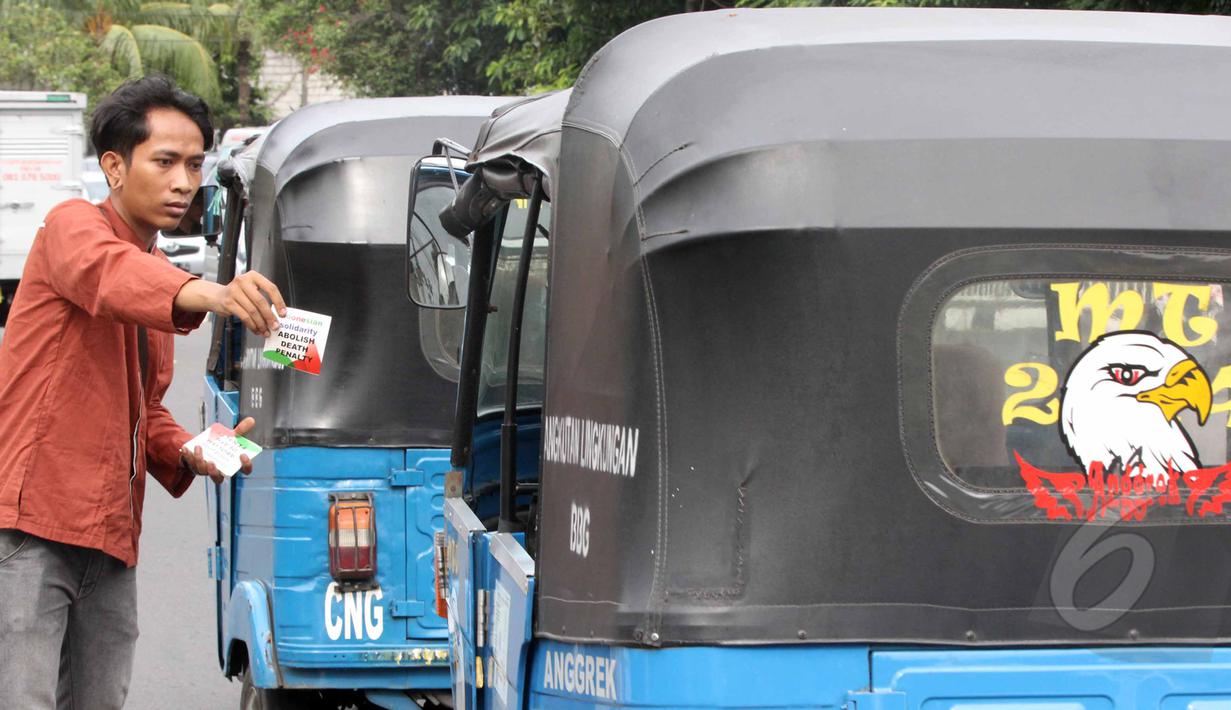Salah satu pengunjuk rasa membagikan stiker saat aksi di Megaria, Jakarta, Jumat, (24/4/2015). Pengunjuk rasa mengkritisi sistem peradilan yang tidak transparan dan tidak independen dalam memberikan hukuman mati. (Liputan6.com/Helmi Afandi)