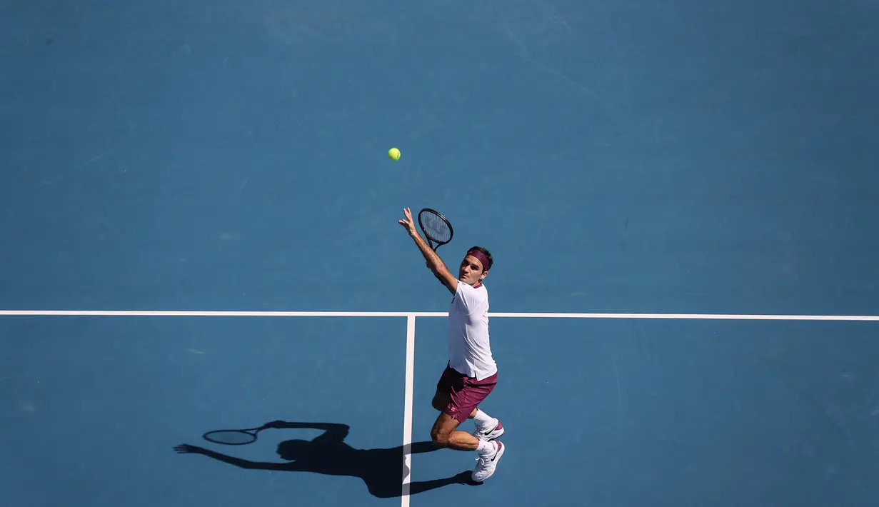 Petenis Swiss, Roger Federer, melakukan servis saat melawan petenis AS, Tennys Sandgren, pada perempat final Australia Open 2020 di Melbourne, Selasa (28/1). Federer menang 6-3, 2-6, 2-6, 7-6 (10-8), 6-3 atas Sandgren. (AFP/David Gray)