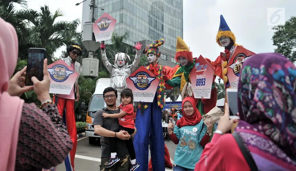 Warga foto bersama badut yang tengah menyosialisasikan sistem tilang Electronic Traffic Law Enforcement (ETLE) kepada pengunjung car free day (CFD) di Bundaran HI, Jakarta, Minggu (25/11). (Merdeka.com/Iqbal Nugroho)