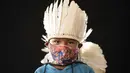 Ezinaldo dos Santos (6) dari kelompok etnis pribumi Sateré Mawé mengenakan pakaian tradisional sukunya dan masker saat pandemi virus corona COVID-19 di komunitas Gaviao, dekat Manaus, Brasil, Jumat (29/5/2020). (AP Photo/Felipe Dana)
