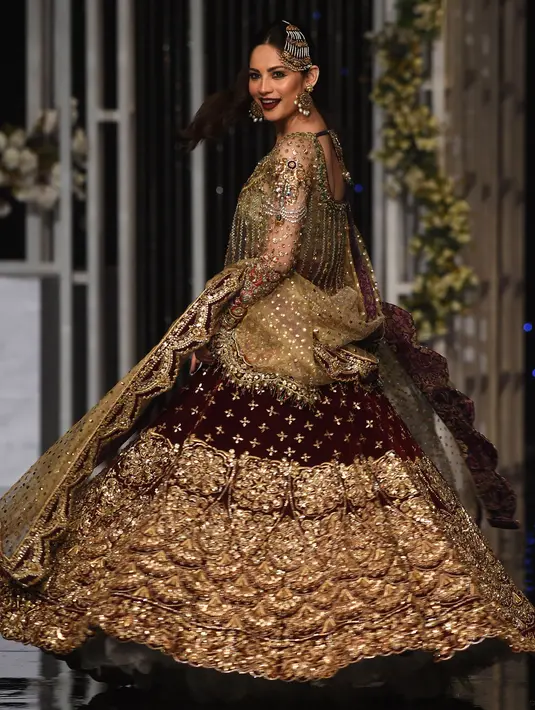 Aktris Neelam Muneer mengenakan busana rancangan desainer Dnnus Dlrar selama Pantene Hum Bridal Couture Week di Lahore, Minggu (9/12). Kreasi gaun pengantin yang ditampilkan didominasi kain sari yang menjadi ciri khas wanita Pakistan. (ARIF ALI / AFP)
