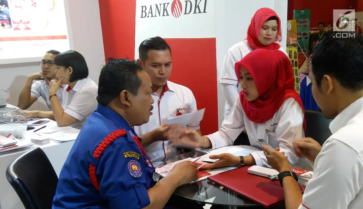 Karyawan Bank DKI menjelaskan aplikasi JakOne Mobile kepada pengunjung Pekan Raya Jakarta di Jakarta (23/5). JakOne Mobile dapat digunakan sebagai alat pembayaran pada merchant yang sudah bekerjasama. (Liputan6.com/Pool/Budi)