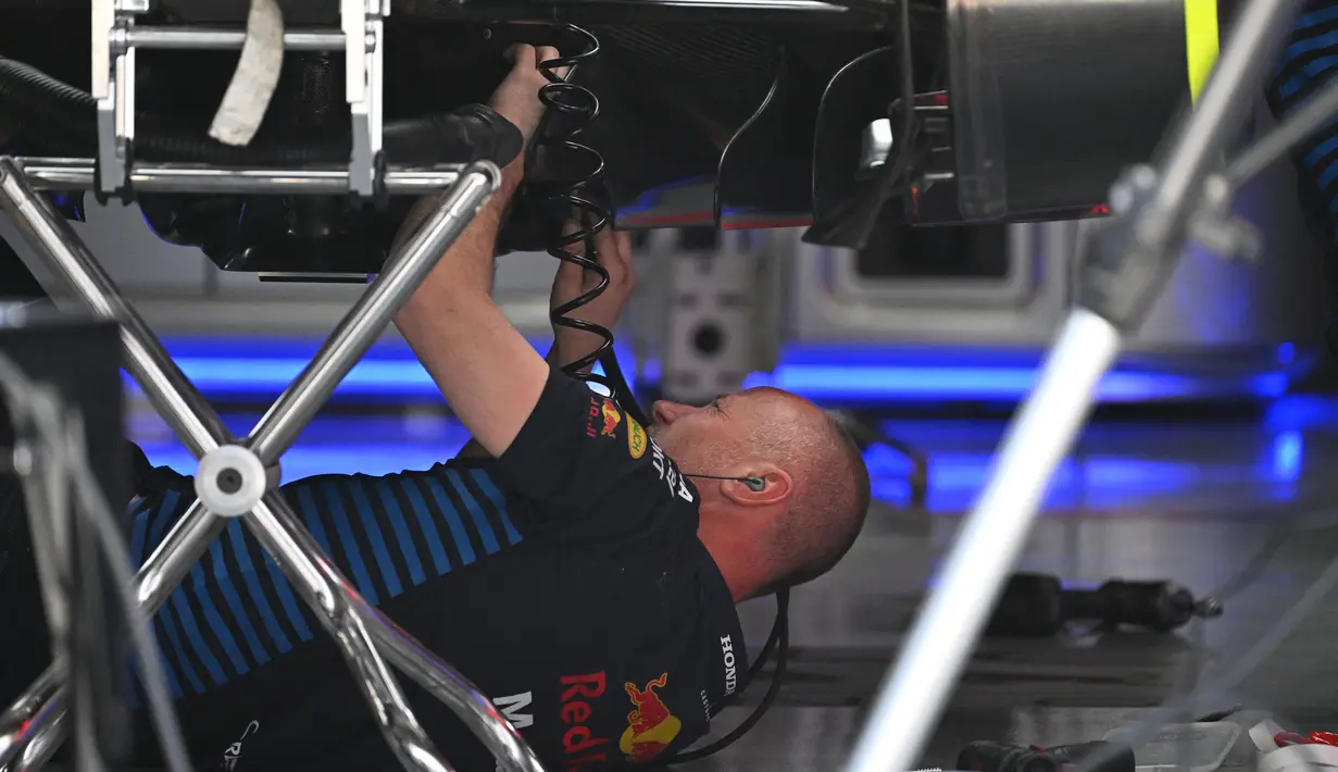 Seorang mekanik bekerja di bawah mobil pembalap Red Bull Racing asal Belanda, Max Verstappen di Shanghai pada 18 April 2024. (GREG BAKER/AFP)