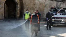 Seorang pegawai pemerintahan kota mendisinfeksi jalan saat lockdown di Kota Khan Younis, Jalur Gaza, Palestina, 19 Desember 2020. Lockdown penuh dan jam malam diberlakukan di Tepi Barat dan Jalur Gaza untuk mengendalikan meningkatnya jumlah infeksi dan kematian akibat COVID-19. (Xinhua/Yasser Qudih)