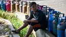 Warga berharap Pemerintah Kota Banda Aceh segera berkoordinasi dengan pihak terkait, termasuk Pertamina dan agen distribusi, untuk memastikan pasokan gas kembali normal. Tampak dalam foto, seorang anak laki-laki menunggu untuk membeli tabung gas di sebuah stasiun pengisian dan pembelian LPG setelah banjir bandang di Banda Aceh pada Rabu 17 Desember 2025. (CHAIDEER MAHYUDDIN/AFP)