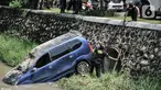 Petugas Dinas Perhubungan Kota Bekasi saat evakuasi mobil yang terperosok ke kali di Harapan Indah, Bekasi, Jawa Barat, Rabu (16/2/2022). Mobil jenis Avanza tersebut jatuh ke dalam kali usai mengalami kecelakaan tunggal akibat tergelincir saat melintasi tikungan. (merdeka.com/Iqbal S. Nugroho)