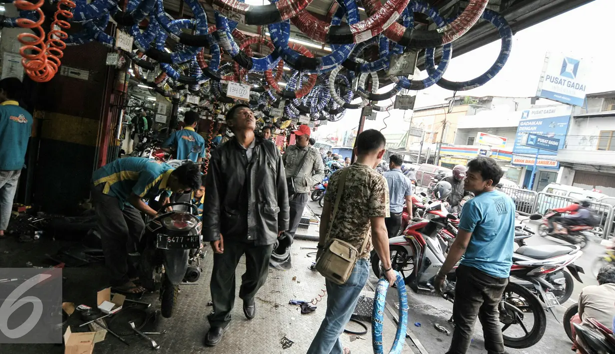 Pelanggan jasa servis motor tengah melihat aksesoris kendaraan di bengkel di kawasan Pasar Minggu, Jakarta, Kamis (30/6). Jelang Lebaran, bengkel motor ramai dikunjungi pemudik motor. (Liputan6.com/Yoppy Renato)