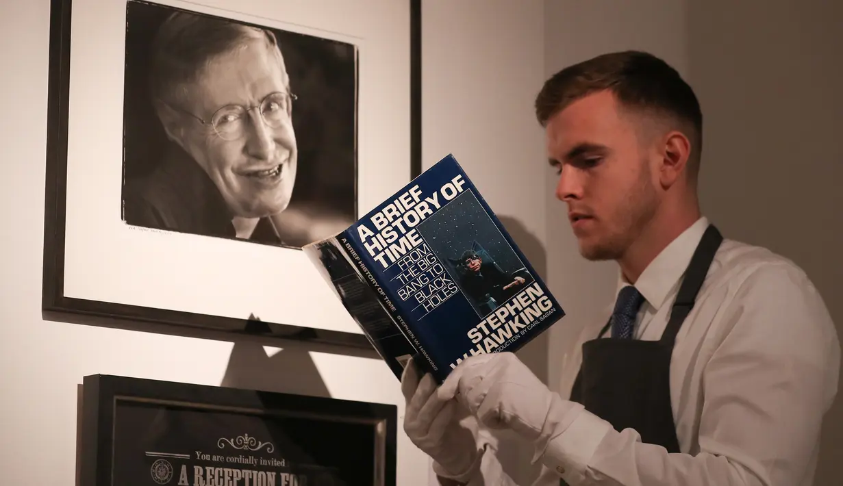 Asisten galeri berpose dengan salinan buku “A History of Time” yang ditandatangani dengan cap jempol oleh fisikawan Stephen Hawking selama sesi pemotretan untuk acara pelelangan di Balai Lelang Christie, London, Selasa (30/10). (Daniel LEAL-OLIVAS/AFP)