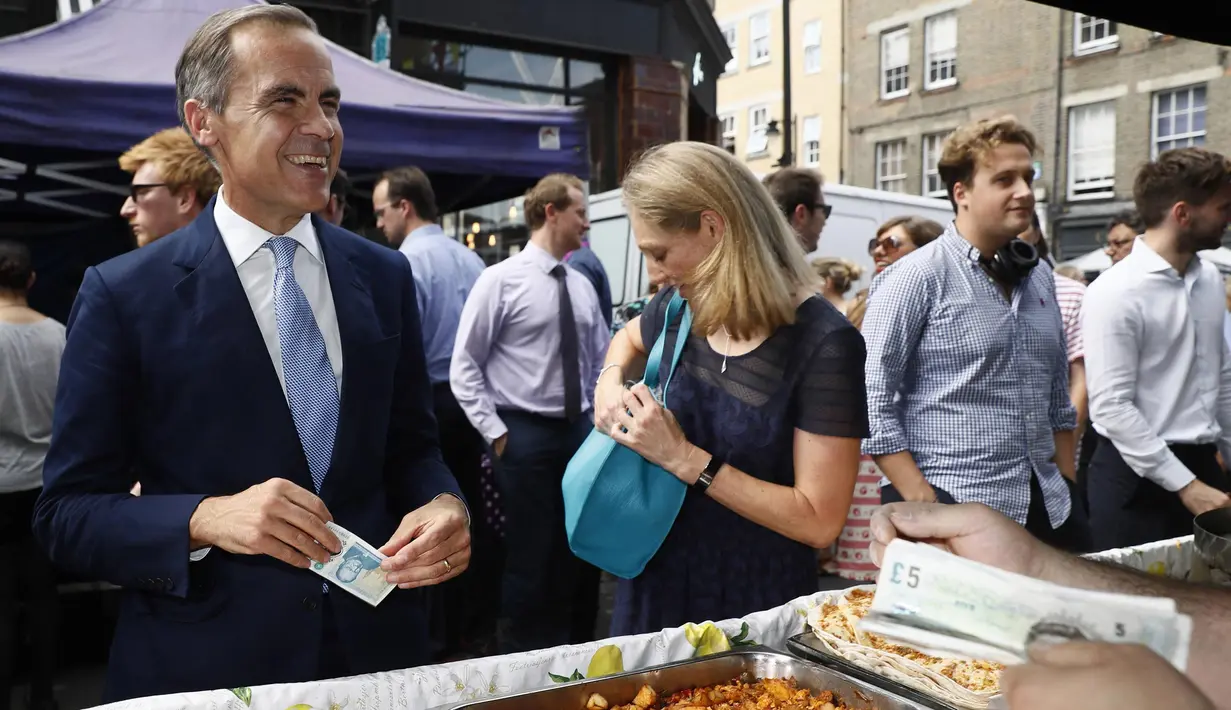 Gubernur Bank Inggris, Carney singgah untuk membeli makan siang di Whitecross Street Market di London, Selasa (13/9). Carney menunjukkan kepada penjual tentang kelebihan uang keluaran baru Bank Inggris. (REUTERS / Stefan Wermuth)