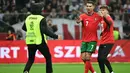 Seorang steward berlari untuk mengusir salah satu suporter yang masuk ke lapangan untuk berswafoto dengan pemain bintang, Cristiano Ronaldo selama pertandingan sepak bola UEFA Nations League 2024/2025, Liga A Grup A1 Polandia vs Portugal di Stadion PGE Narodowy, Warsawa, Polandia pada Sabtu 12 Oktober 2024 atau Minggu (13/10/2024) dini hari WIB. (Sergei GAPON/AFP)