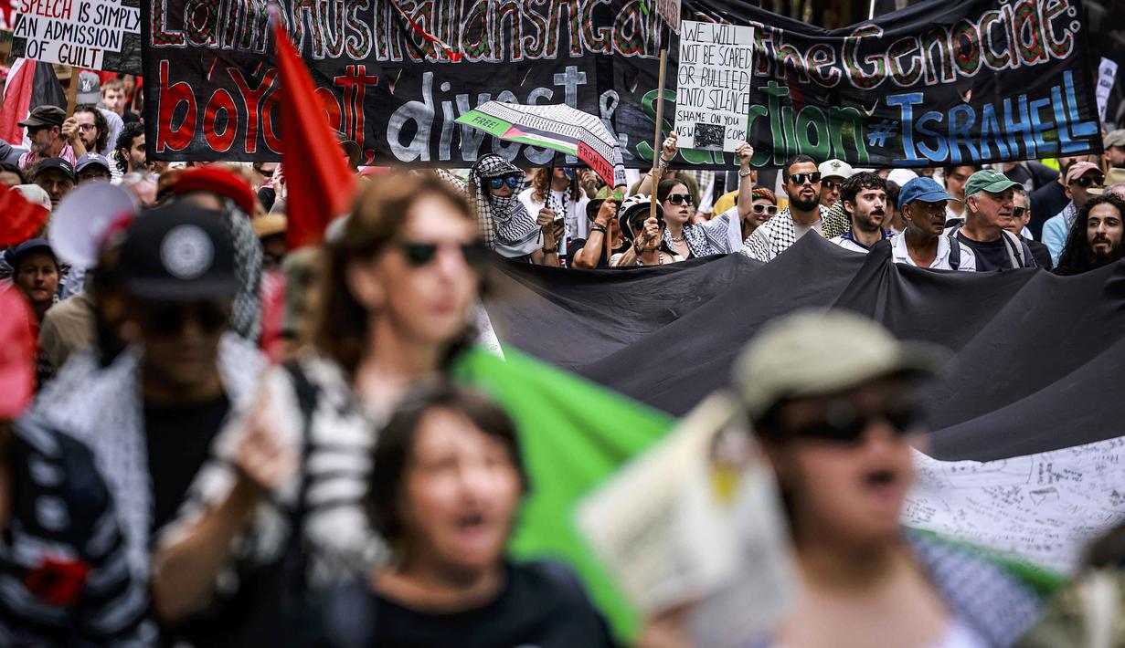 Mereka kembali berunjuk rasa mendesak penghentian serangan militer Israel di wilayah Gaza. Tampak dalam foto, para demonstran pro-Palestina membawa bendera, spanduk, dan plakat saat mereka berbaris berunjuk rasa di jalanan kota Sydney, Australia, Minggu 22 Februari 2026. (DAVID GRAY/AFP)
