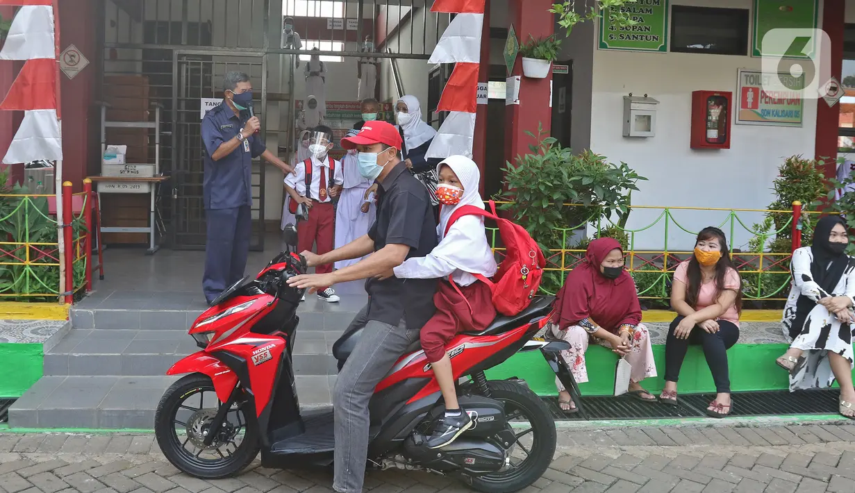 Orang tua siswa menjemput anaknya seusai pembelajaran tatap muka (PTM) di SDN 05 Kalisari, Jakarta, Senin (30/8/2021). Pemprov DKI  menggelar PTM di tengah pandemi covid-19 mulai 30 Agustus 2021 secara terbatas dengan kapasitas 50 persen pada setiap satuan pendidikan. (Liputan6.com/Herman Zakharia)