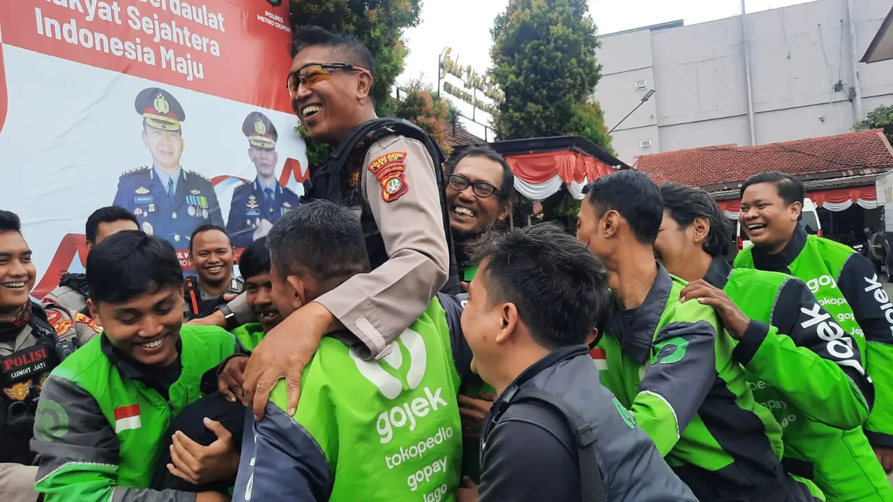 Puluhan ojol saat mengarak dan menggendong Kompol Winam Agus usai perna tugas sebagai aparat kepolisian Polres Metro Depok.